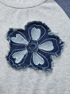 Raglan shirt with a distressed denim embroidered flower patch detail.