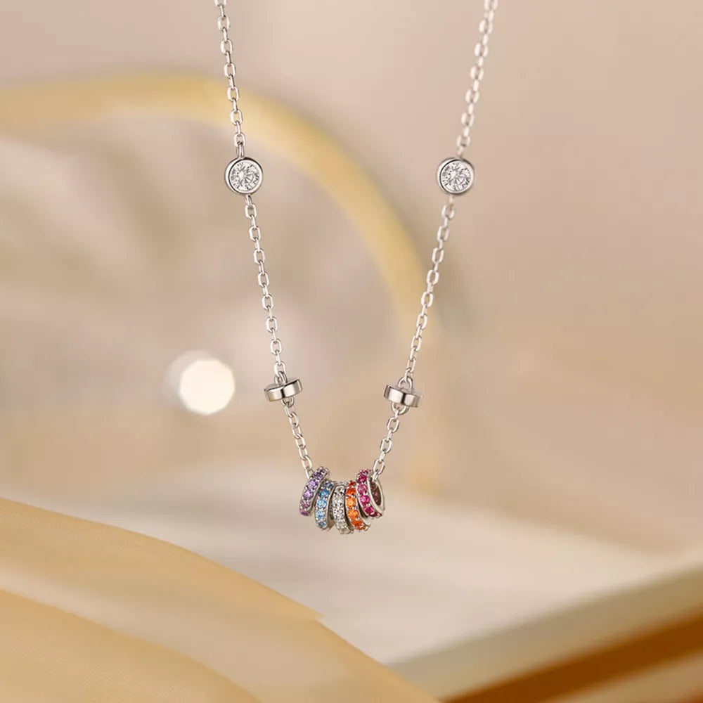 Silver necklace with bezel-set cubic zirconia and a cluster of colorful rings.