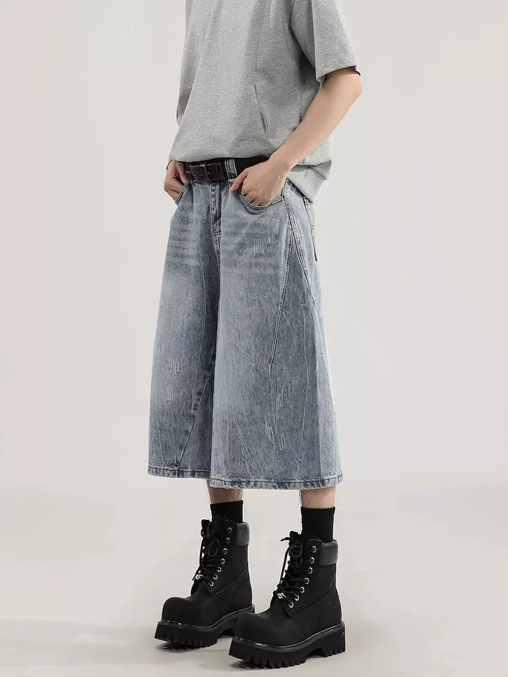 Men's light wash denim capris with a relaxed fit and wide leg, styled with a grey t-shirt and black boots.