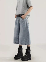 Men's light wash denim capris with a relaxed fit and wide leg, styled with a grey t-shirt and black boots.