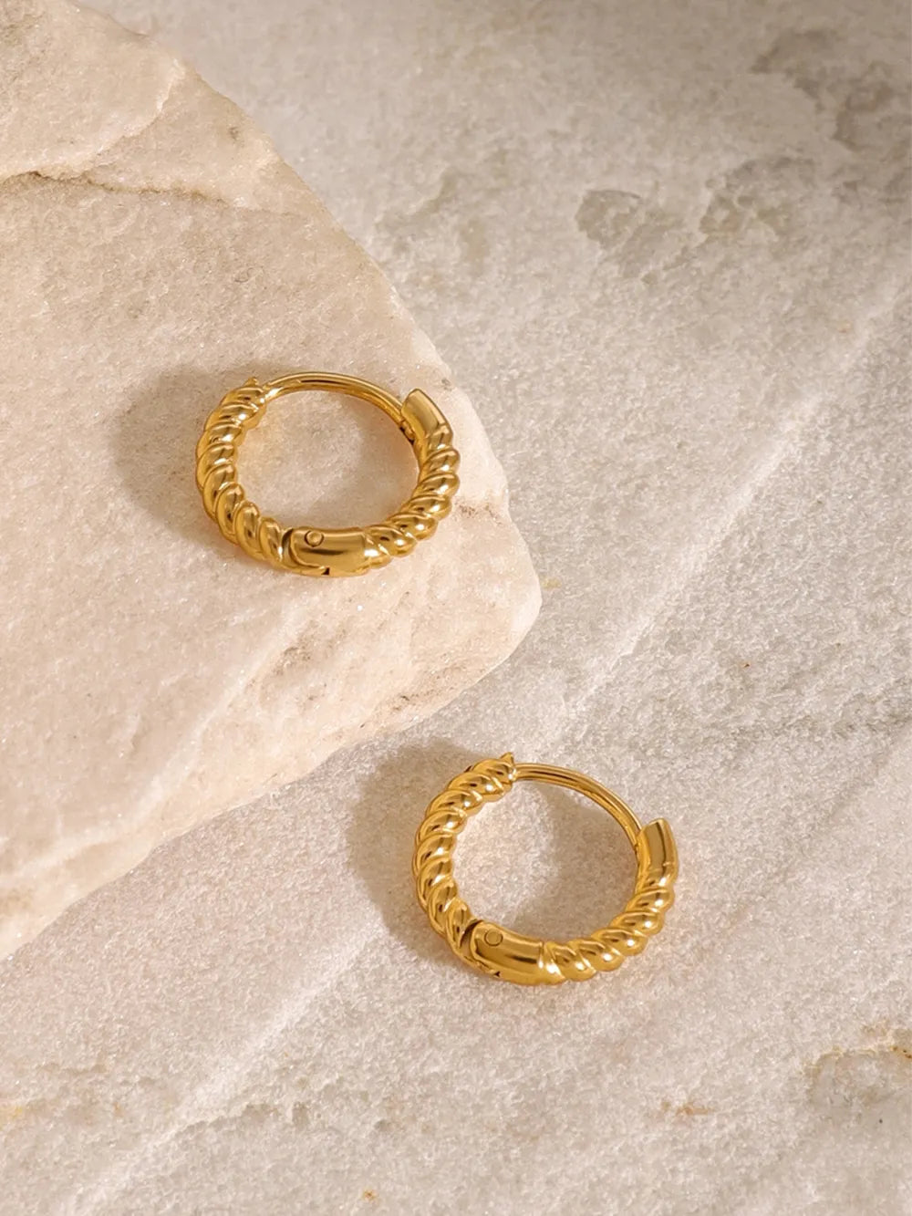 Gold twisted mini hoop earrings with a textured design.
