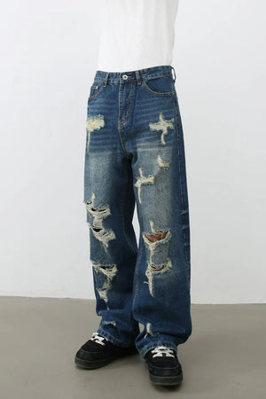 Oversized ripped denim jeans in medium wash with a wide-leg silhouette and distressed details.