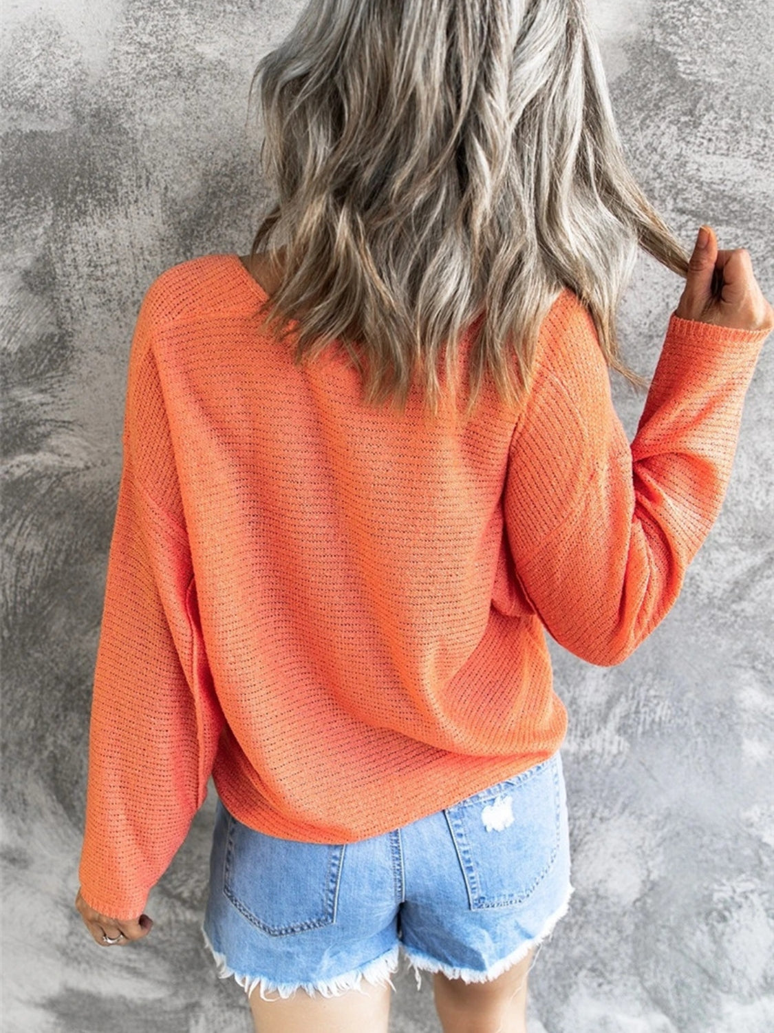 Orange open-knit V-neck drop shoulder sweater with a relaxed fit.