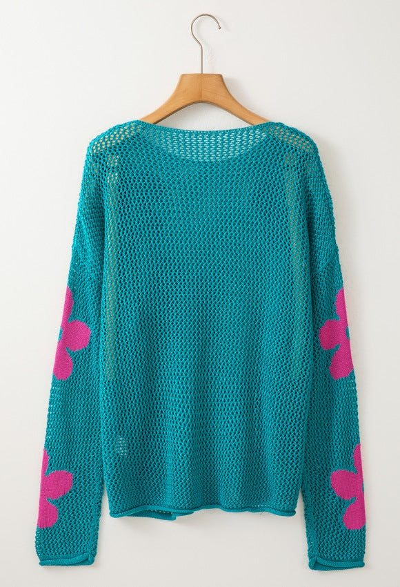 Teal openwork sweater with pink floral intarsia on sleeves.