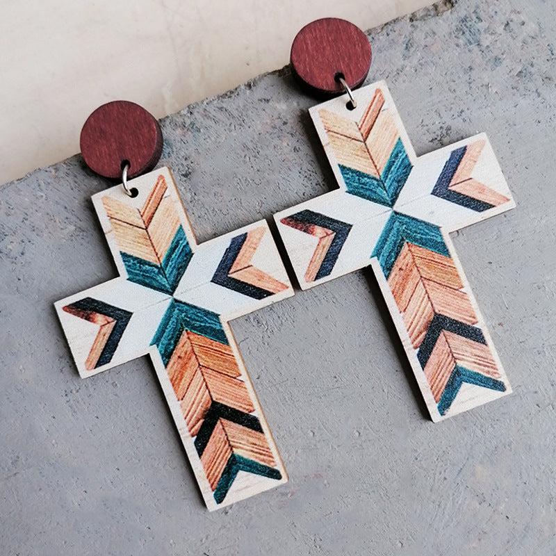 Geometric cross statement earrings with wood post and tribal pattern in beige, teal, and orange.