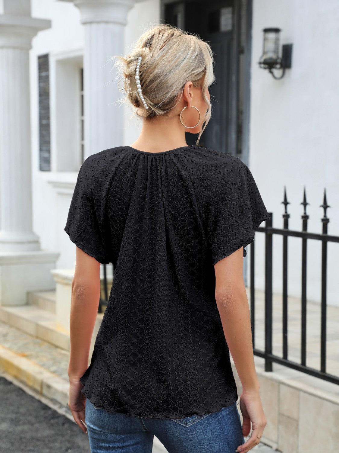 Black perforated tie-neck flutter sleeve blouse with a ruffled hem
