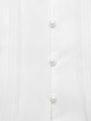 White midi dress with cap sleeves, pearl buttons, and pintuck detail.
