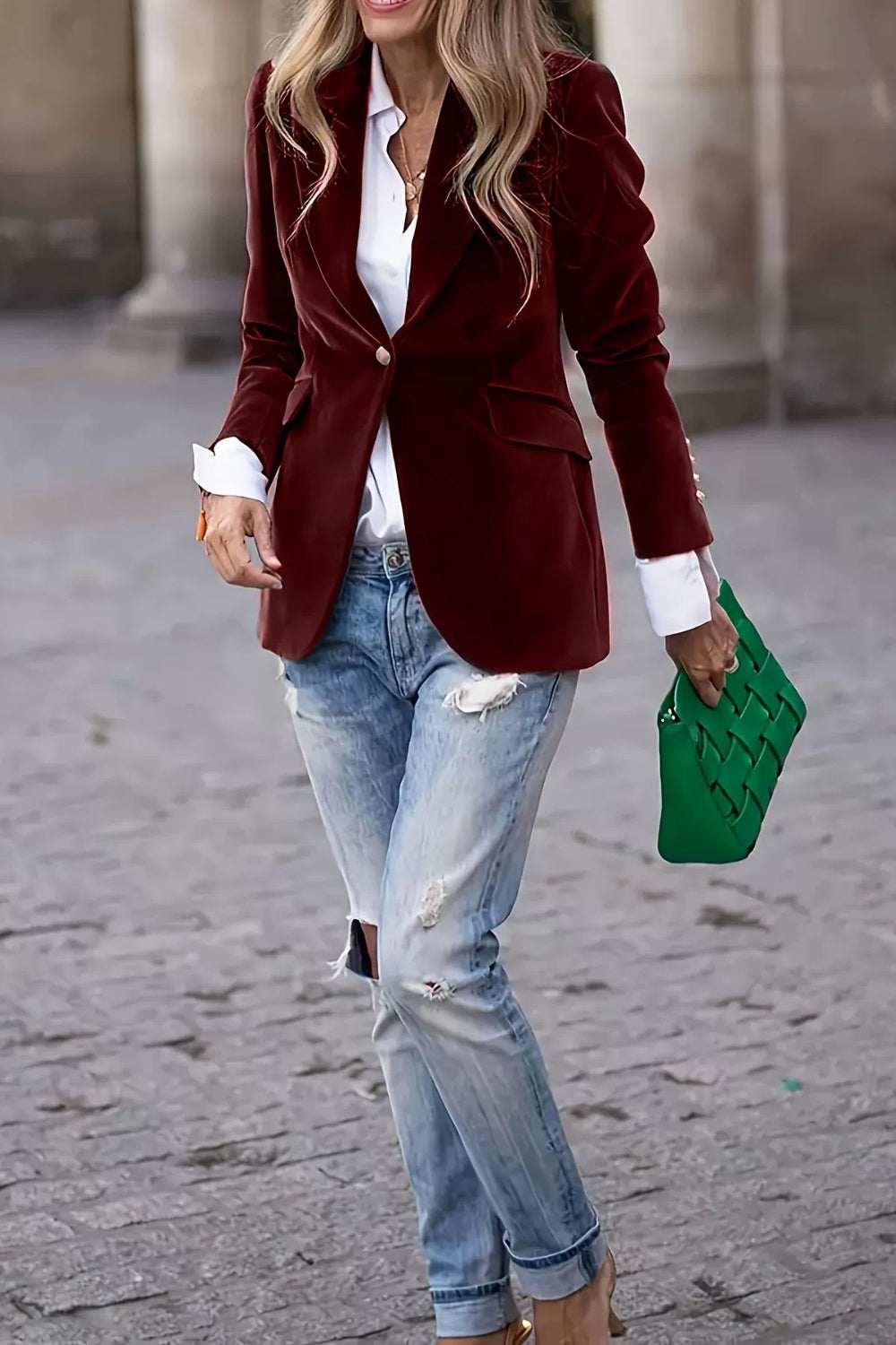 Burgundy velvet blazer with sculpted shoulders and button closure, styled with jeans.
