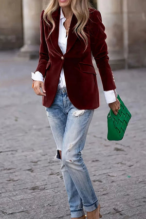 Burgundy velvet blazer with sculpted shoulders and button closure, styled with jeans.