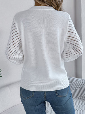 White openwork chevron knit sweater with blouson sleeves and crewneck, styled with jeans.