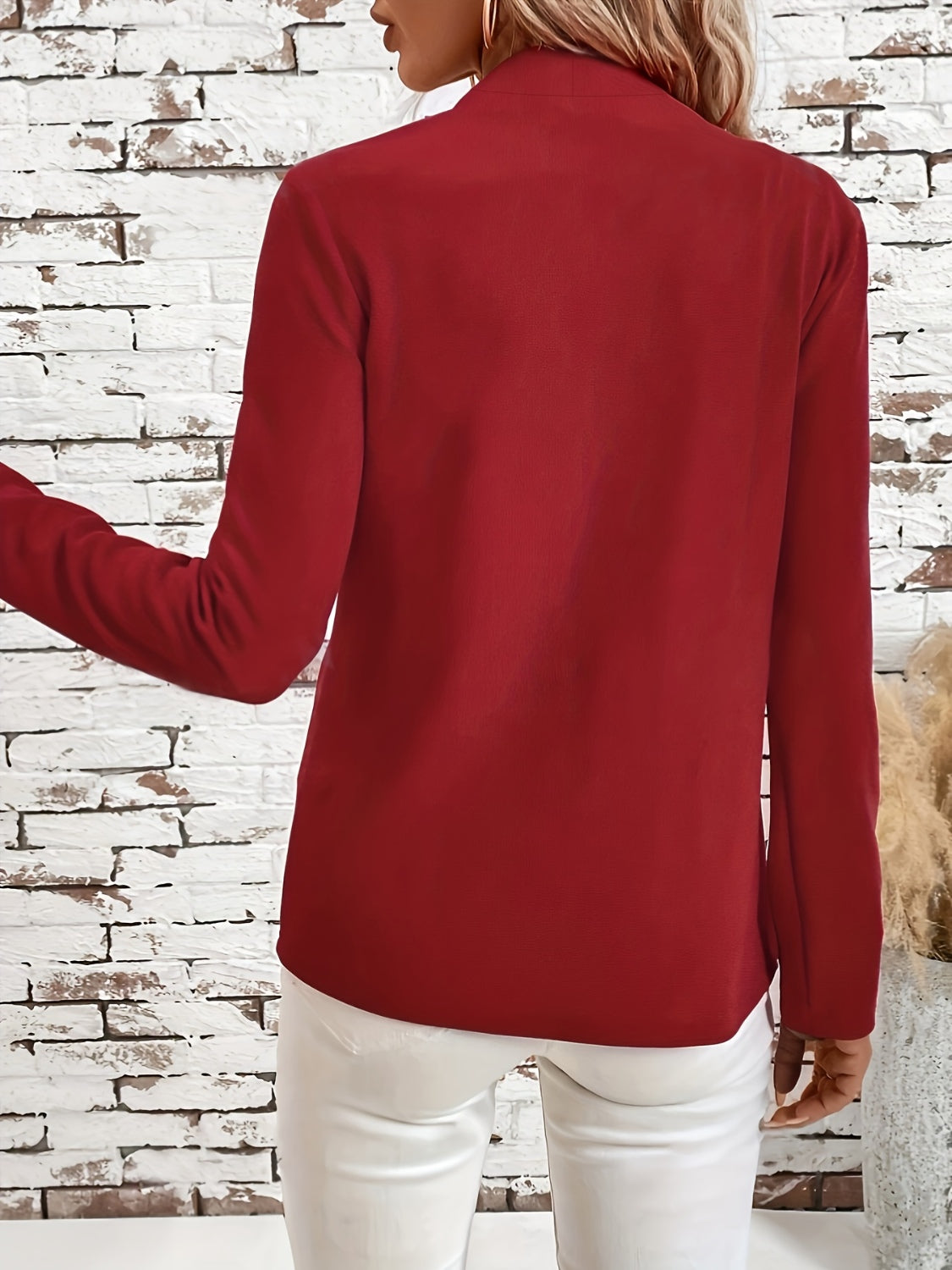 Open-front blazer in rust with clean lines and long sleeves, styled with white pants.