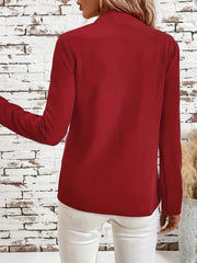 Open-front blazer in rust with clean lines and long sleeves, styled with white pants.