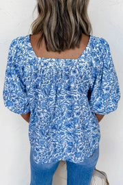 Floral pleated blouse with square neckline and puff sleeves in blue and white print.