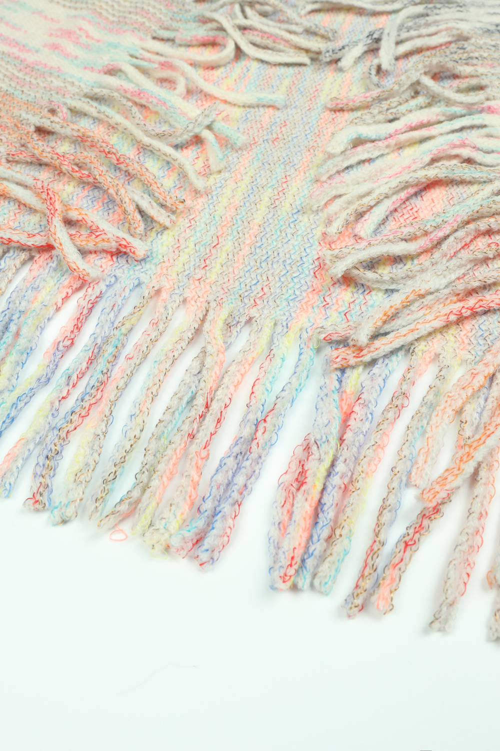 Textured knit cape detail with colorful fringe and a woven pattern.