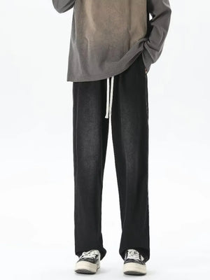 Men's relaxed fit jeans in gradient wash black with white drawstring and loose leg.