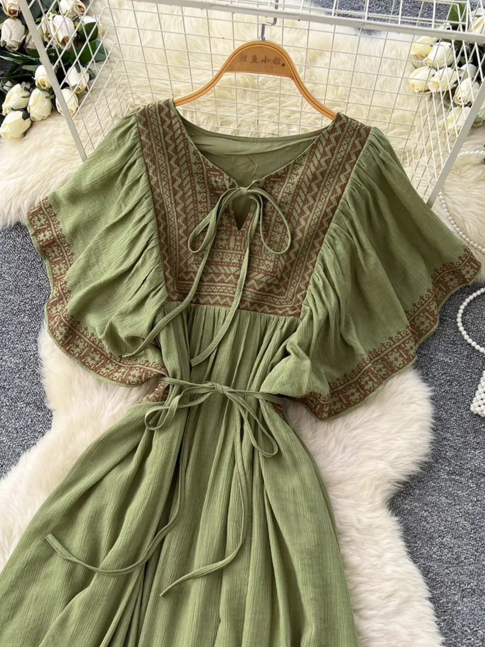 Mint green bohemian maxi dress with V-neck, tie front, embroidered details, and flutter sleeves.