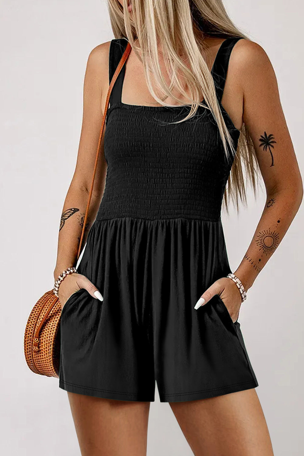 Black smocked bodice romper with square neck, adjustable straps, and pockets.
