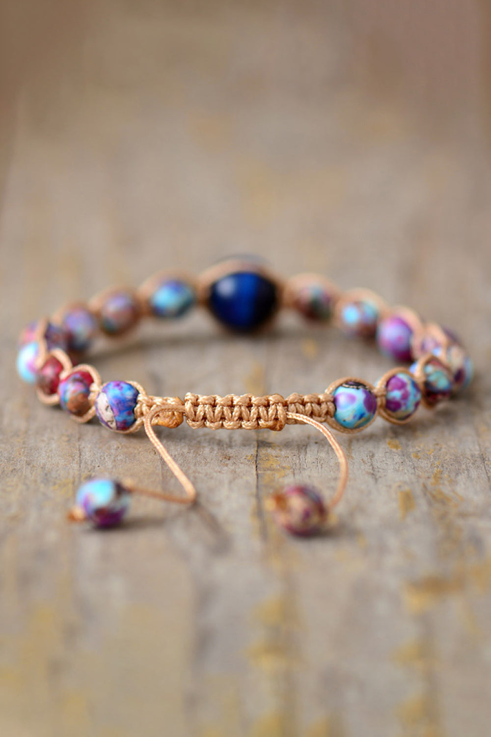Bohemian multicolor jasper beadwork bracelet with adjustable macrame cord and a central blue bead.