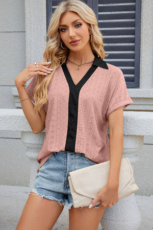 Blush pink perforated polo top with black V-neck panel and collar, short sleeves.