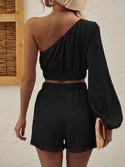 Black textured one-shoulder crop top and cuffed shorts set with one long balloon sleeve.