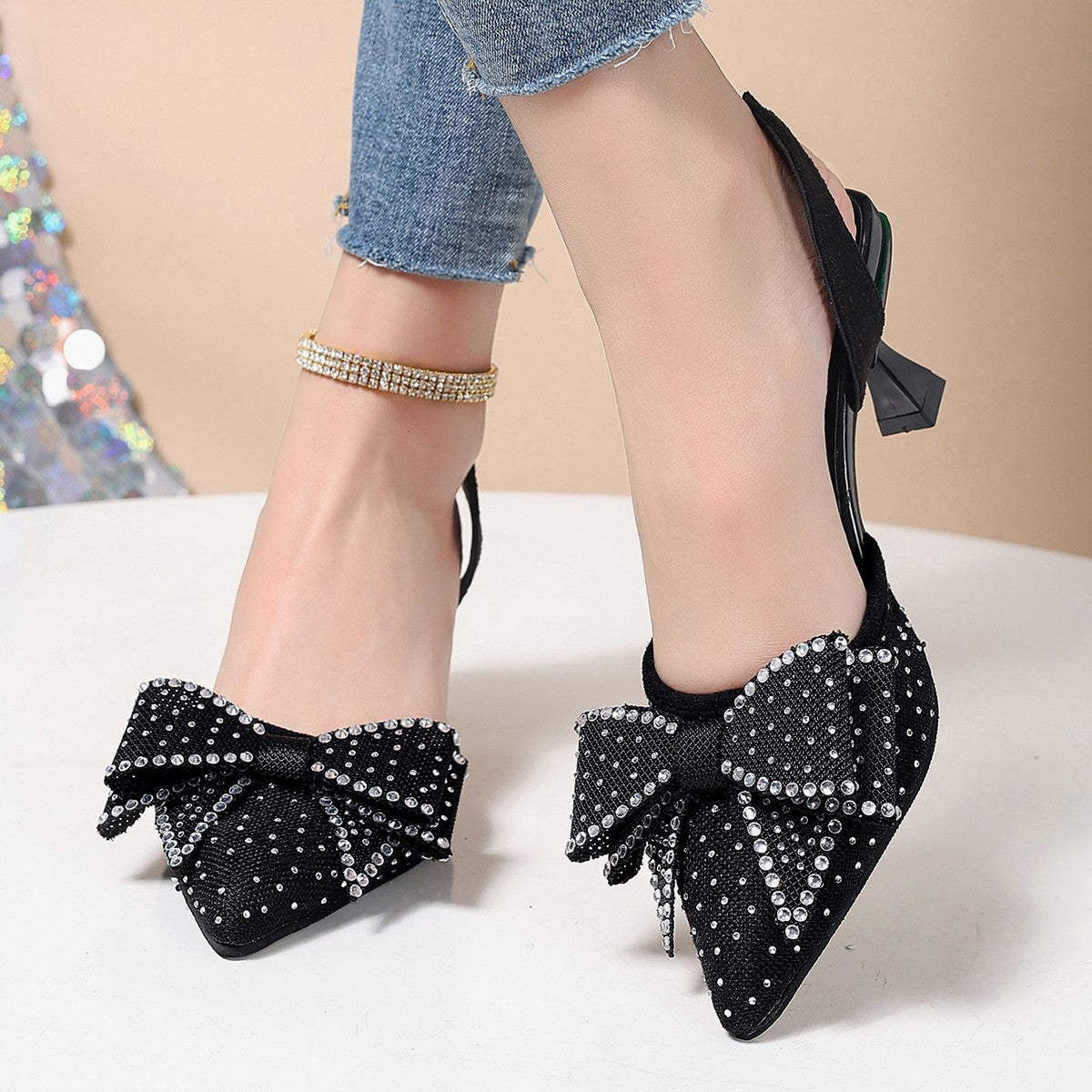 Black slingback heels with rhinestone bowknot detail and pointed toe.