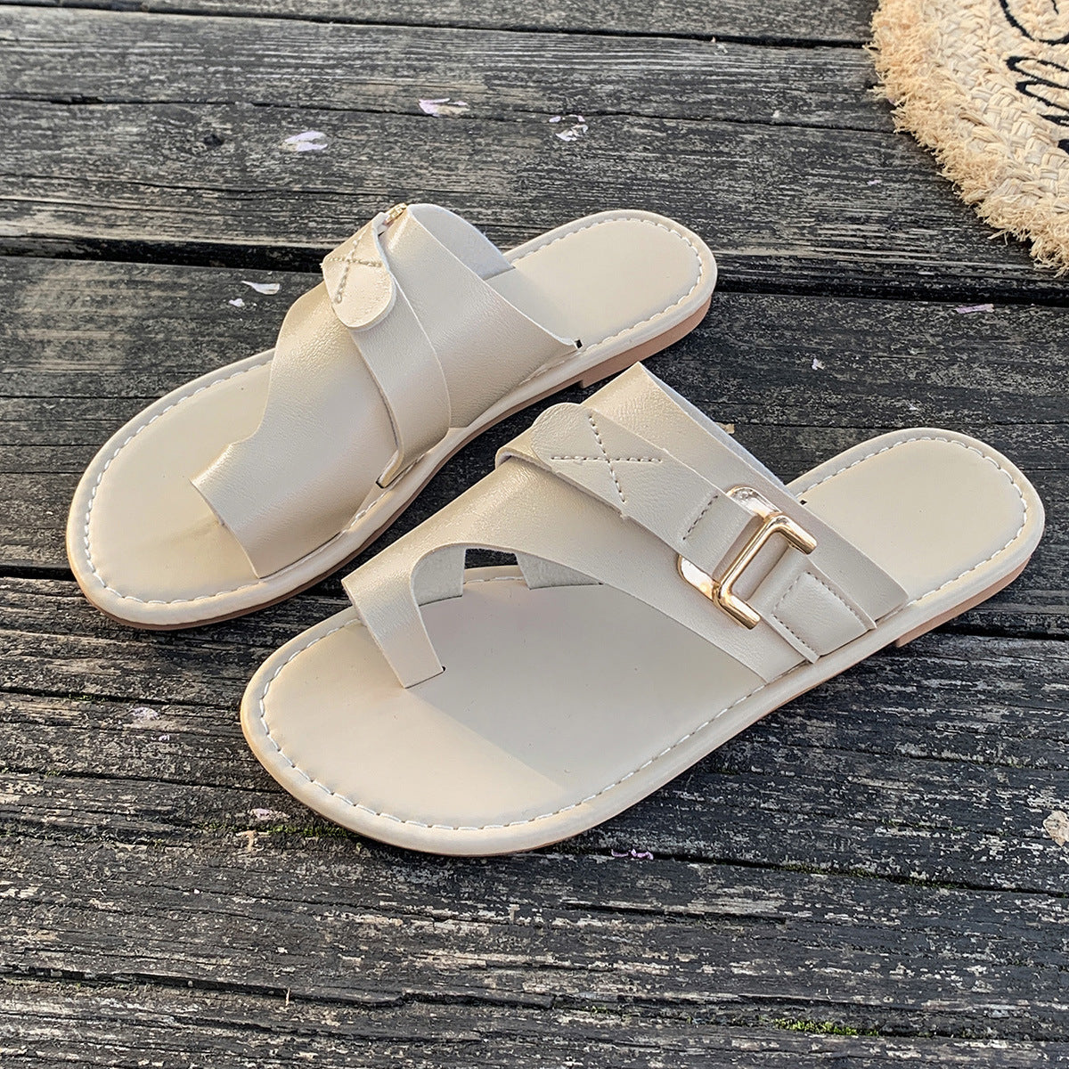 Beige toe loop flat sandals with buckle detail and crisscross straps.