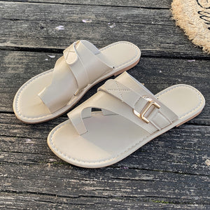 Beige toe loop flat sandals with buckle detail and crisscross straps.