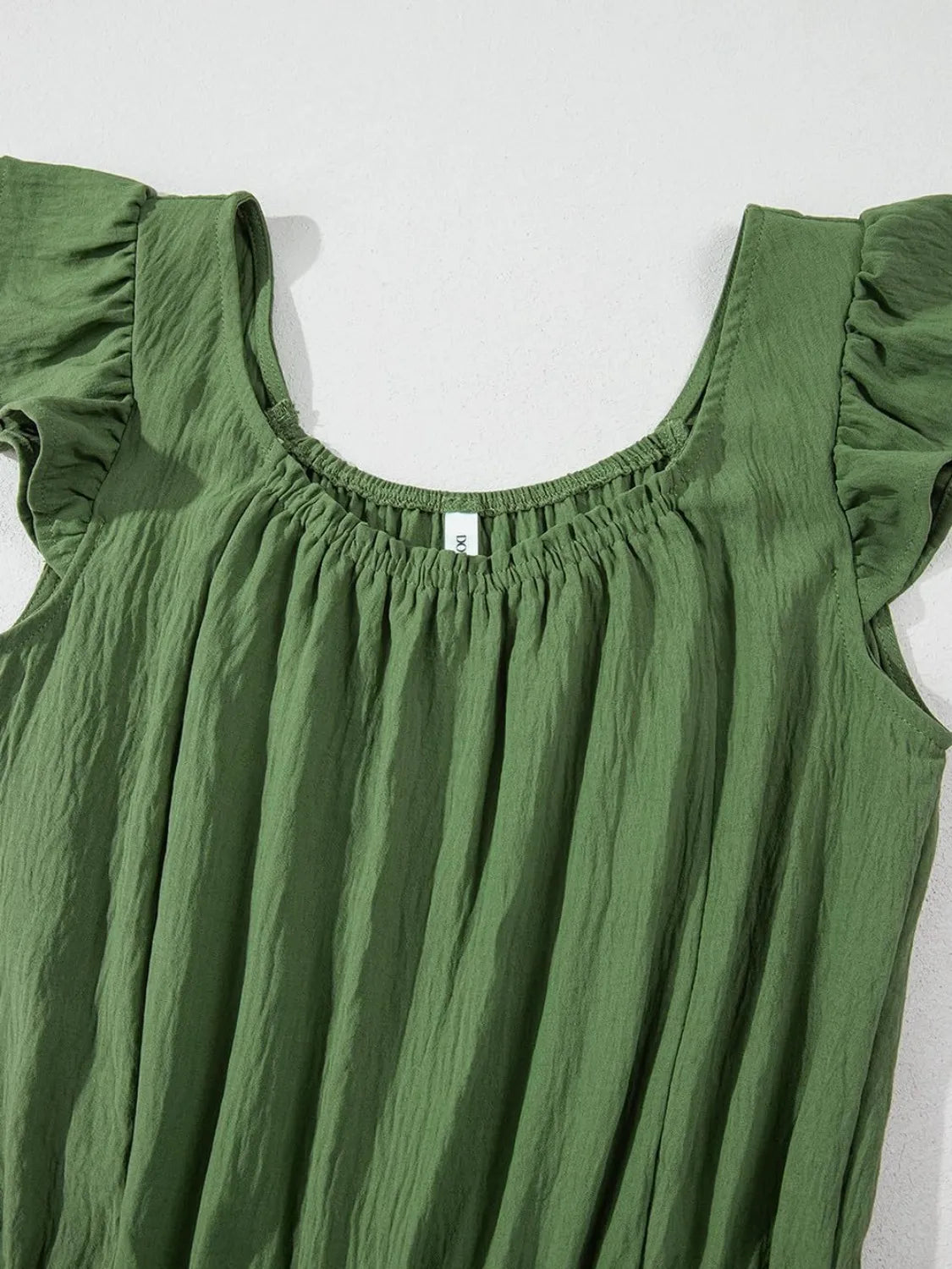Matcha green textured jumpsuit with ruffle sleeves and smocked neckline.