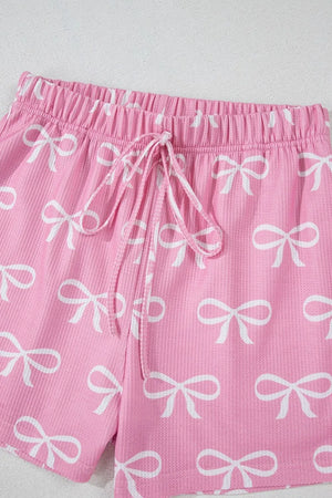 Pink ribbed lounge shorts with white bow print and drawstring waist.