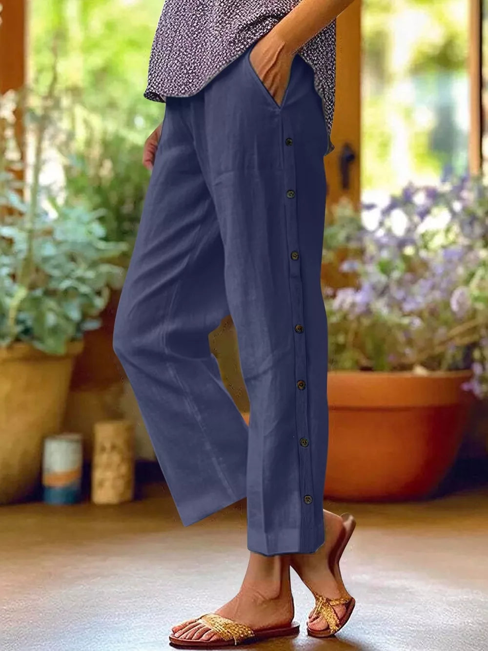 Navy blue relaxed fit pants with decorative buttons down the side and pockets.