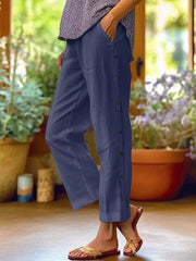 Navy blue relaxed fit pants with decorative buttons down the side and pockets.