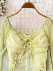 Yellow green maternity blouse with ruffled sleeves, square neck, bow tie, and pearl buttons.