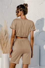 Tan loungewear set with cropped top and shorts, featuring rolled sleeves and elastic waistband.