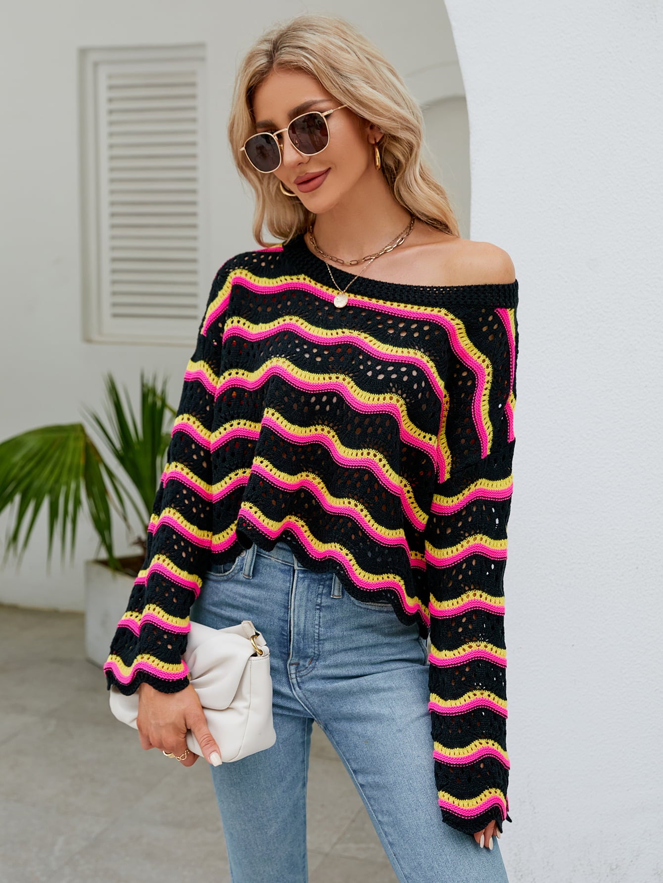 Black crochet crop sweater with pink and yellow zigzag stripes, off-the-shoulder neckline.