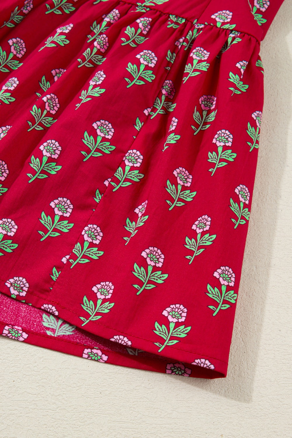 Red cotton mini dress with pink floral print and green leaves.
