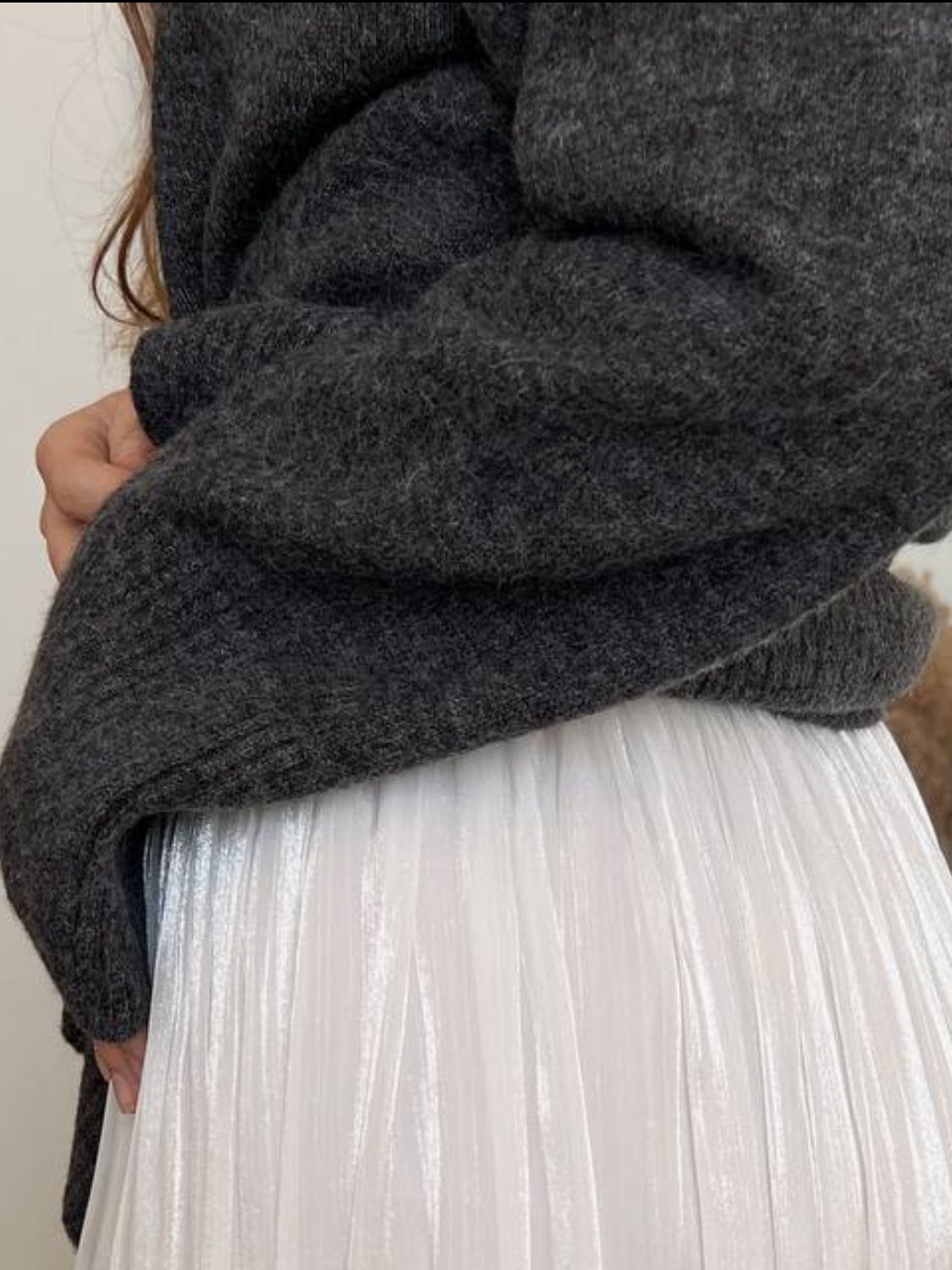 Flared sleeve ribbed turtleneck knit sweater in dark gray acrylic, shown with a white pleated skirt.