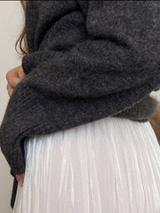Flared sleeve ribbed turtleneck knit sweater in dark gray acrylic, shown with a white pleated skirt.
