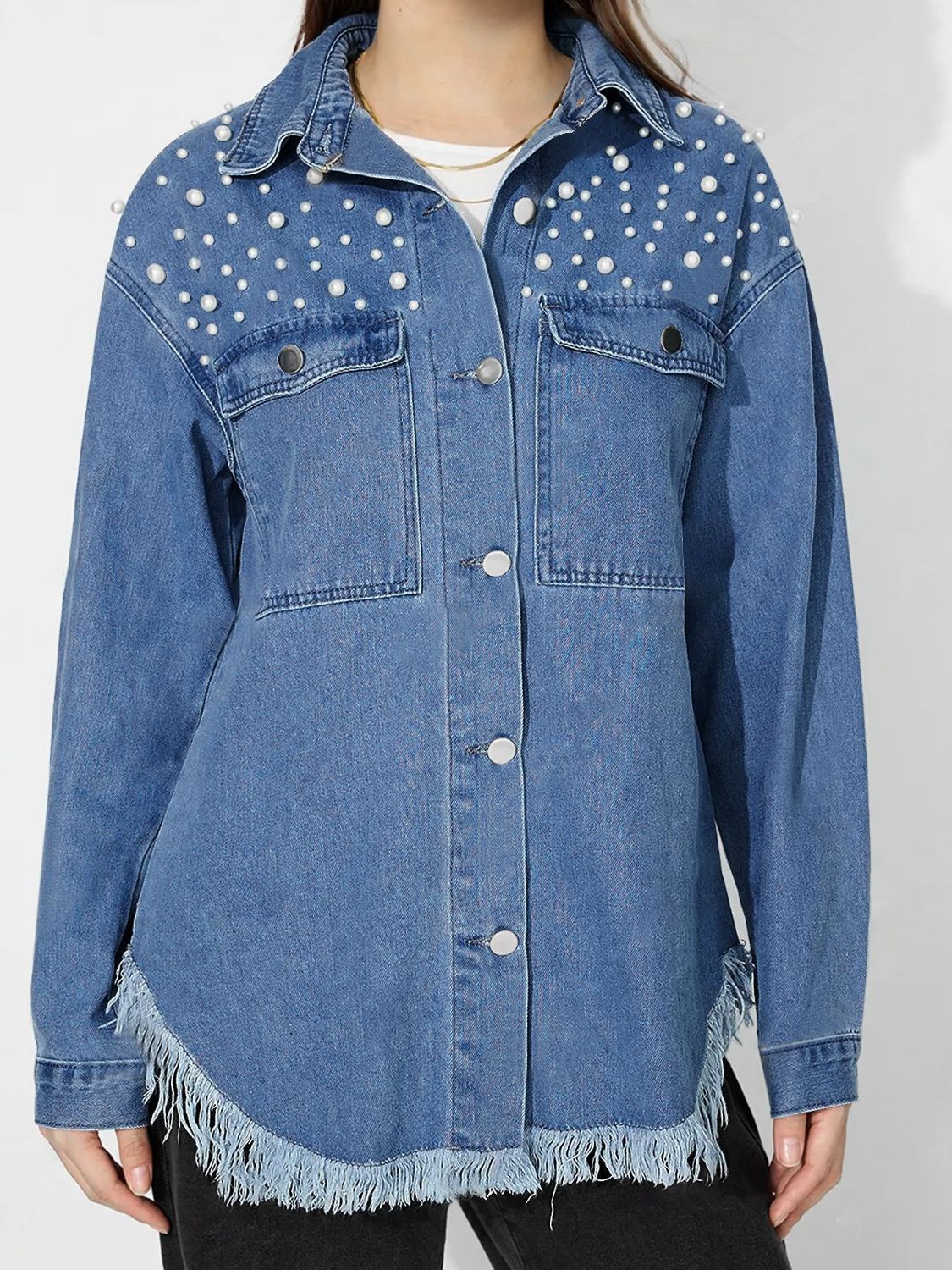 Medium wash denim shirt with pearl embellishments and frayed hem.