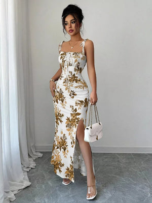 Floral print maxi dress in white with gold floral pattern, tie straps, sweetheart neckline, ruched bodice, and high slit.
