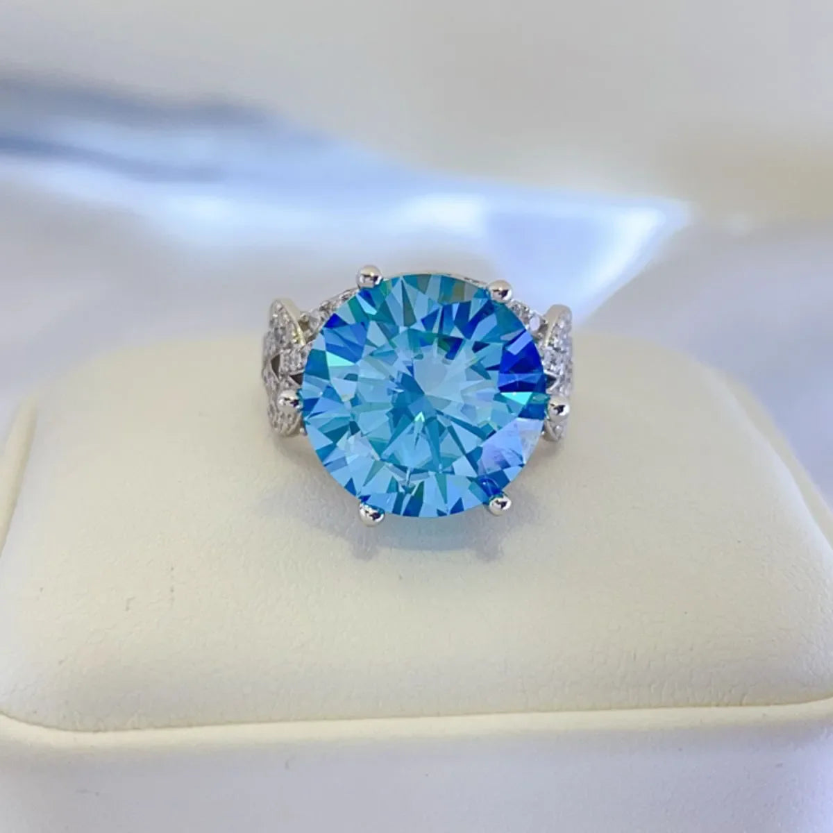 Celestial blue moissanite knot ring with pavé accents and a large round-cut blue stone.