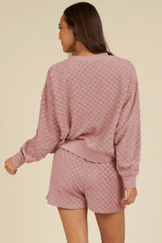 Dusty pink textured checkered loungewear set with crewneck sweatshirt and shorts.