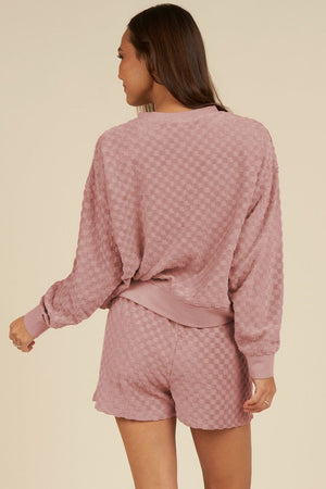 Dusty pink textured checkered loungewear set with crewneck sweatshirt and shorts.