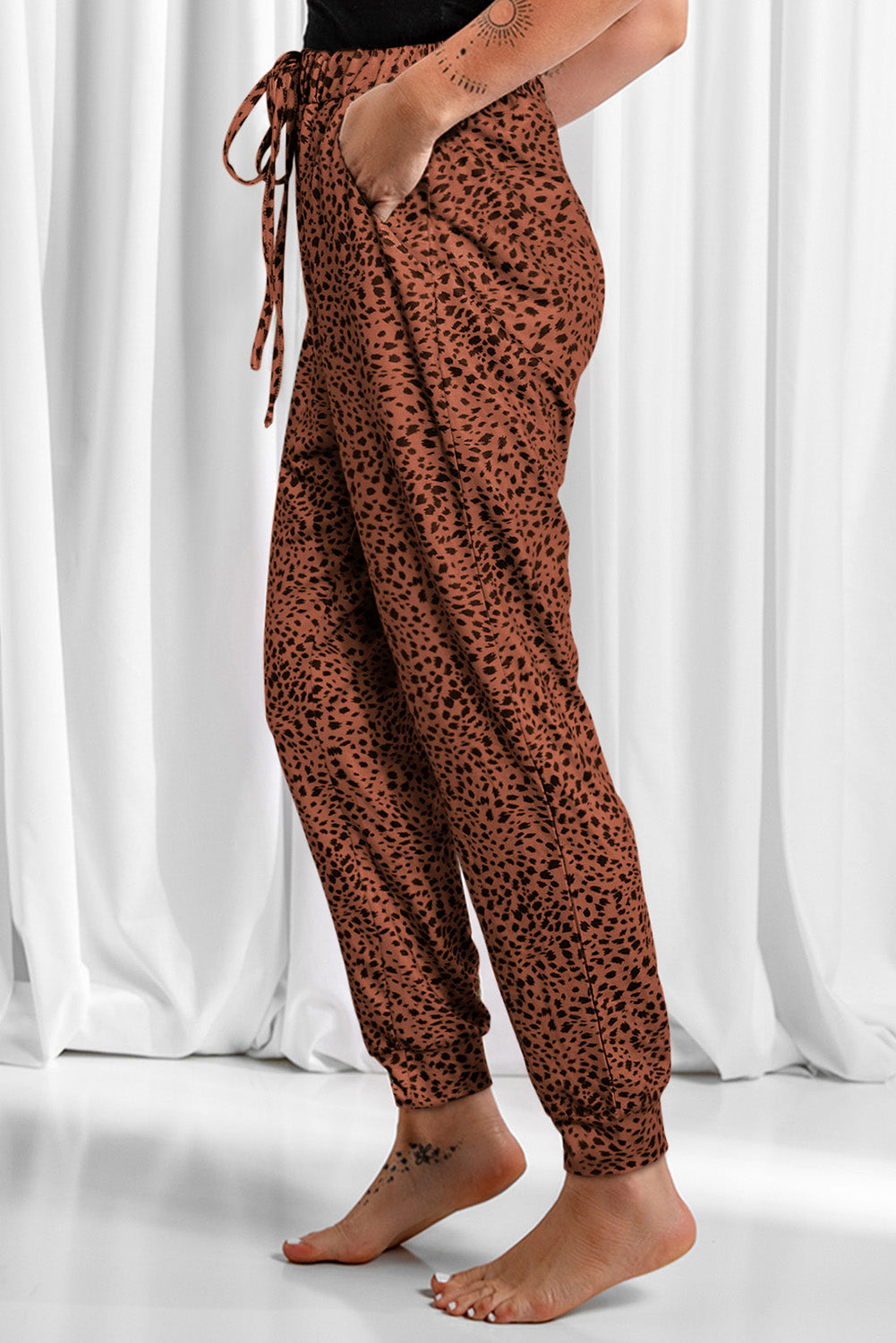 Brown leopard print jogger trousers with drawstring waist and pockets.