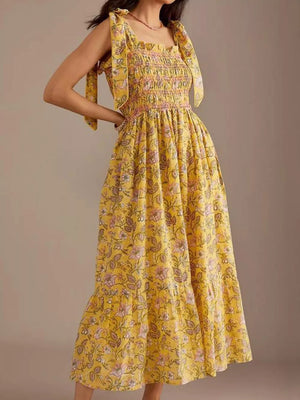 Yellow floral midi dress with tie shoulders and smocked bodice.