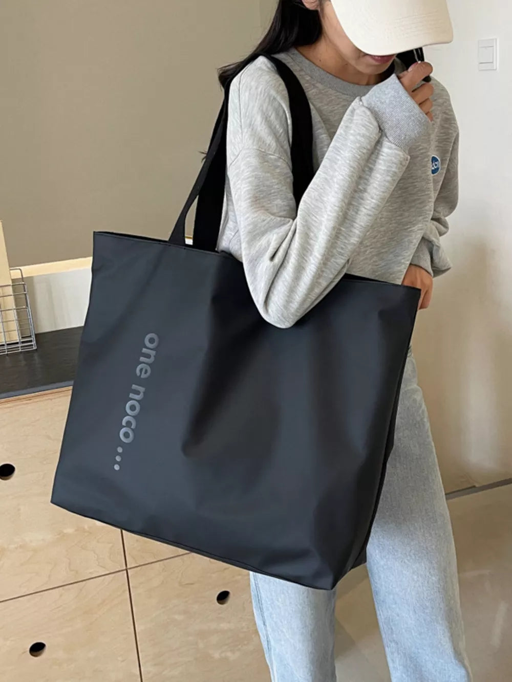 Minimalist black large shoulder bag with text detail, casual tote for women.