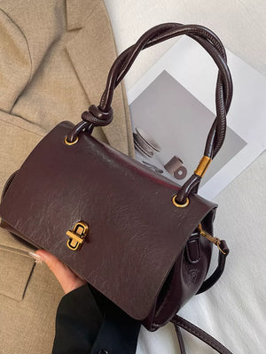 Brown leather crossbody bag with twisted handle and gold clasp closure