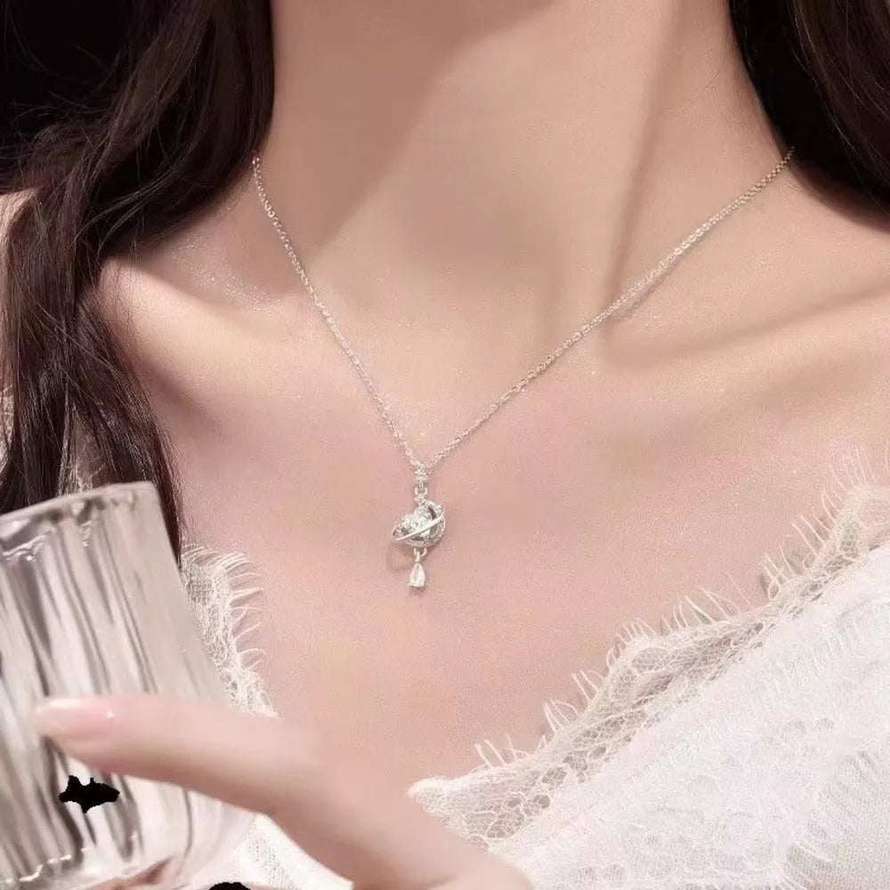 Celestial heart pendant necklace with a sparkling planet charm and teardrop accent.