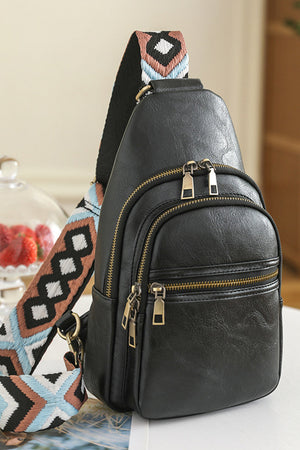 Black geometric strap sling bag with multiple zippered compartments.