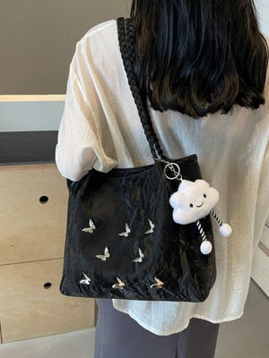 Black shopper bag with braided handle, butterfly details, and cloud charm.