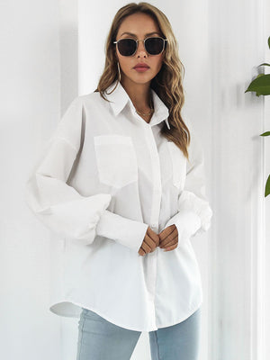 White oversized poplin blouse with blouson sleeves and buttoned cuffs.